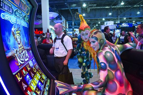 Cirque du Soleil performers pose by a Cirque du Soleil-themed slot machine in the Scientifc Games booth during the Global Gaming Expo (G2E) at the Sands Expo Center Tuesday, Sept. 29, 2015.